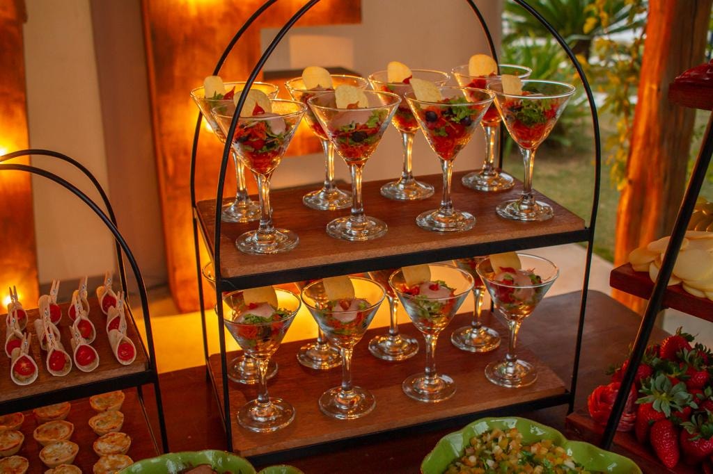 Suporte de taças martini com salada de frutas e chips em evento noturno iluminado