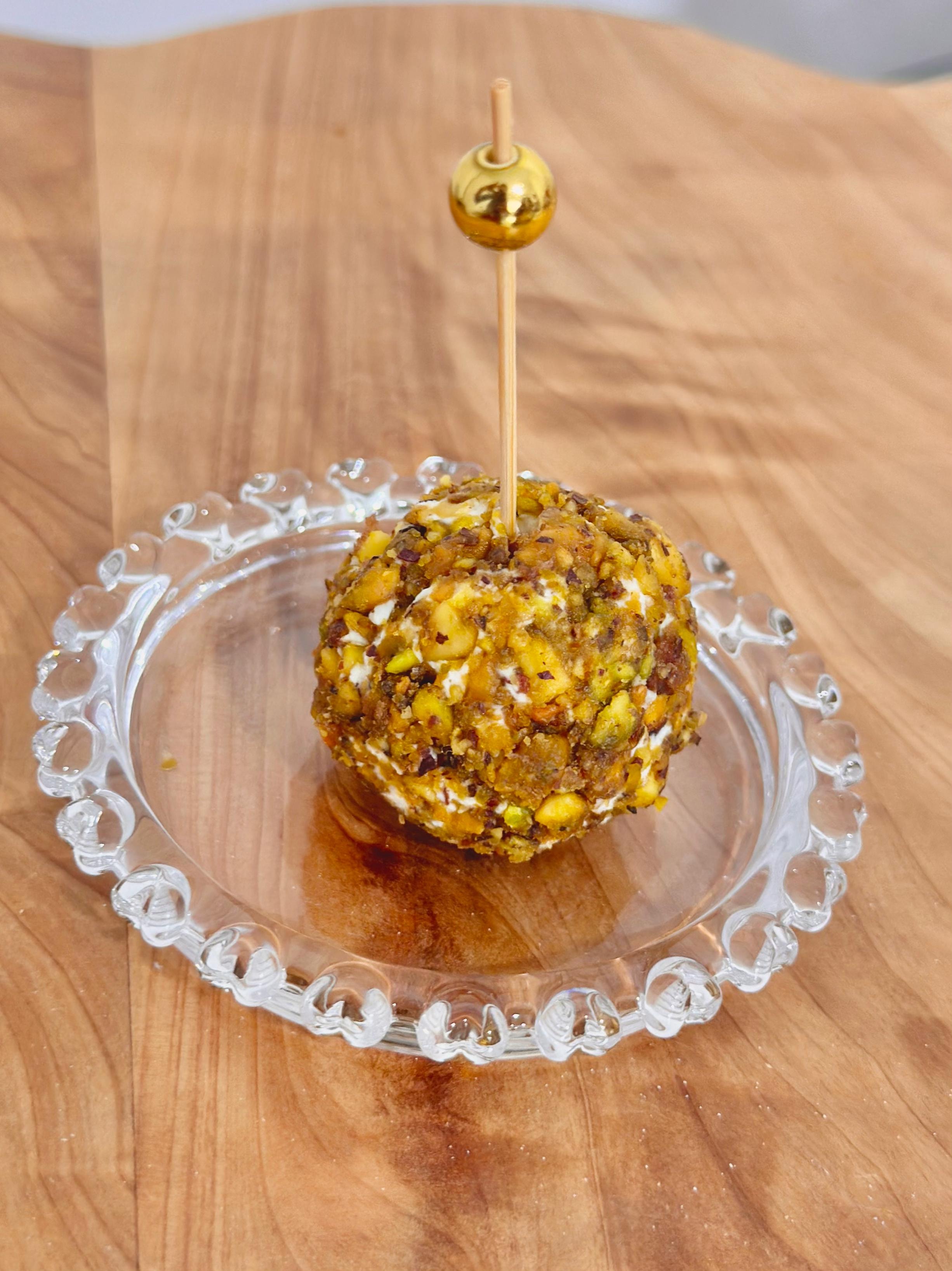 Bolinha de queijo com pistache e palito dourado em prato de cristal