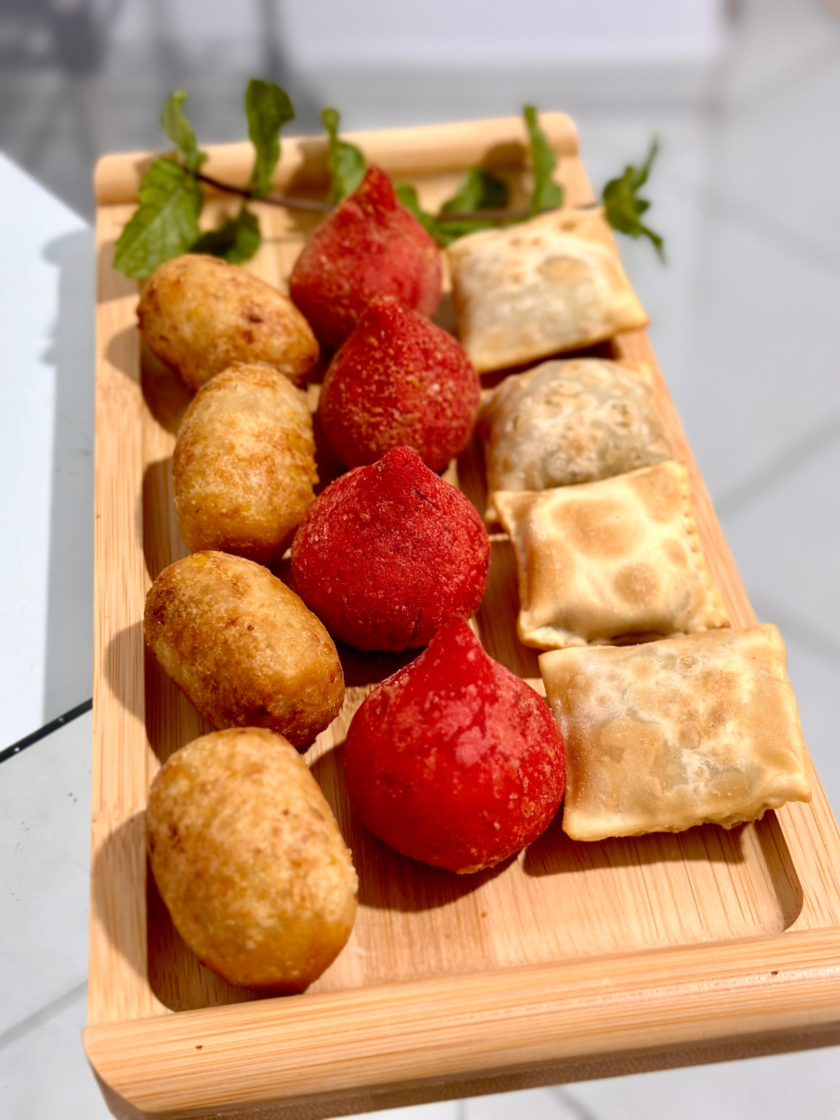 Bandeja com coxinhas, croquetes e pastéis sortidos em tábua de bambu